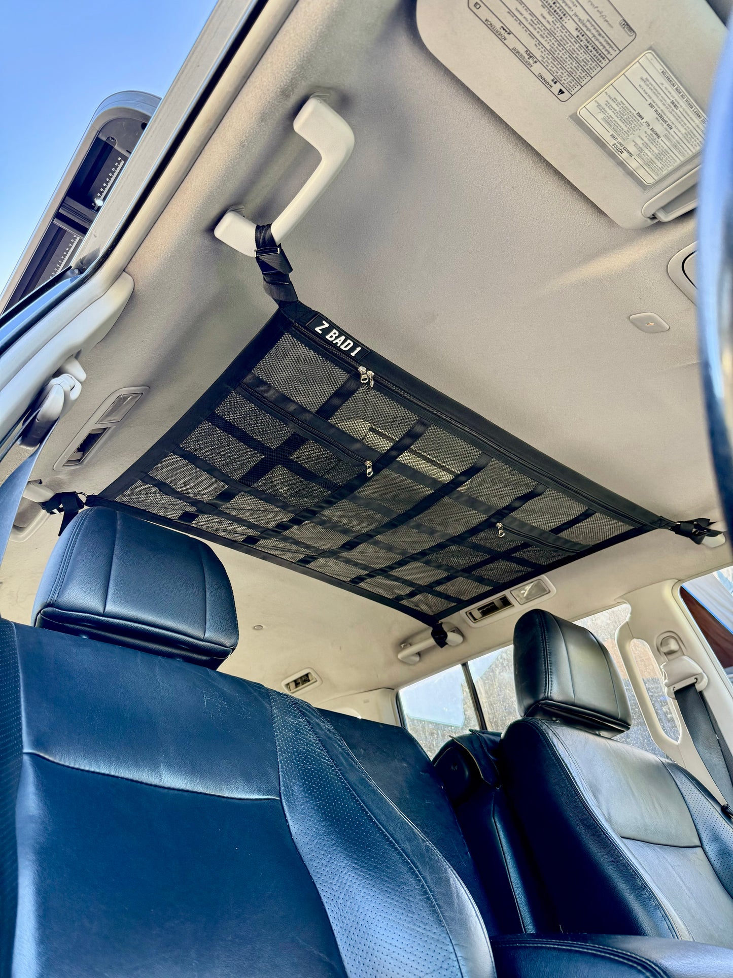ZBAD1 Gen 2 cargo net attached to grab handles across the interior ceiling of a 4WD