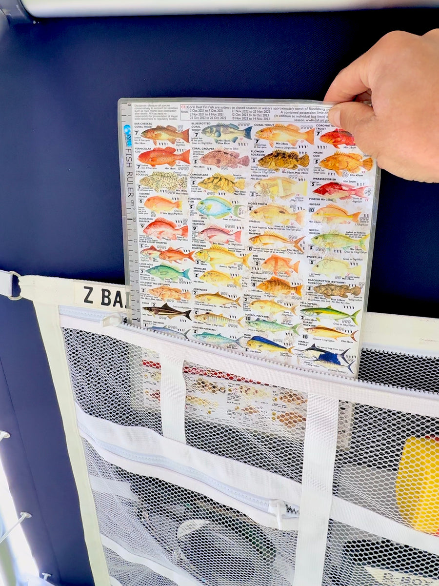 Sliding a fish ruler chart into a pocket on the white ZBAD1 marine grade cargo net on a boat