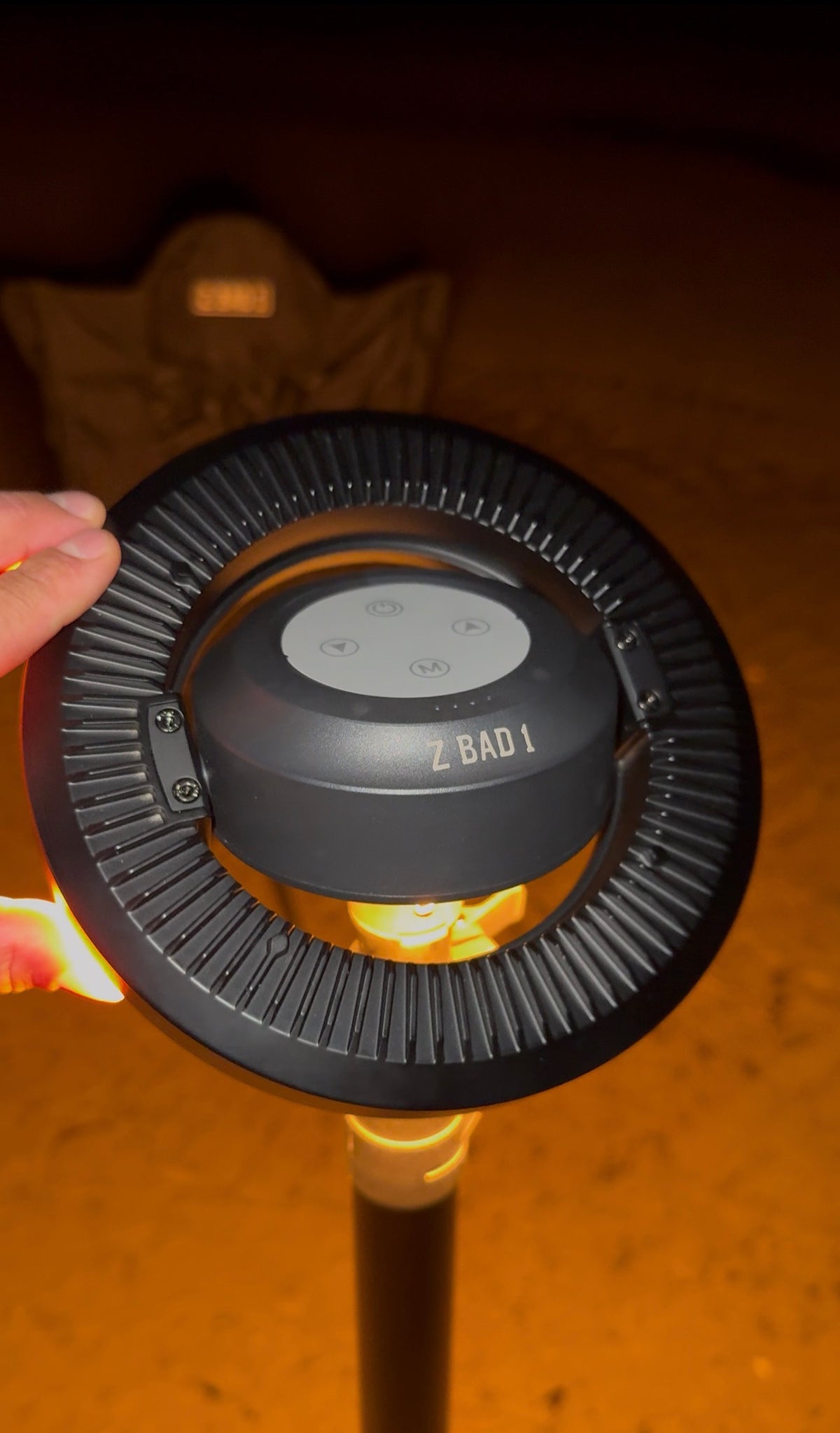 Close-up of the ZBAD1 Ultimate Illuminator ring light glowing warm amber on its mast