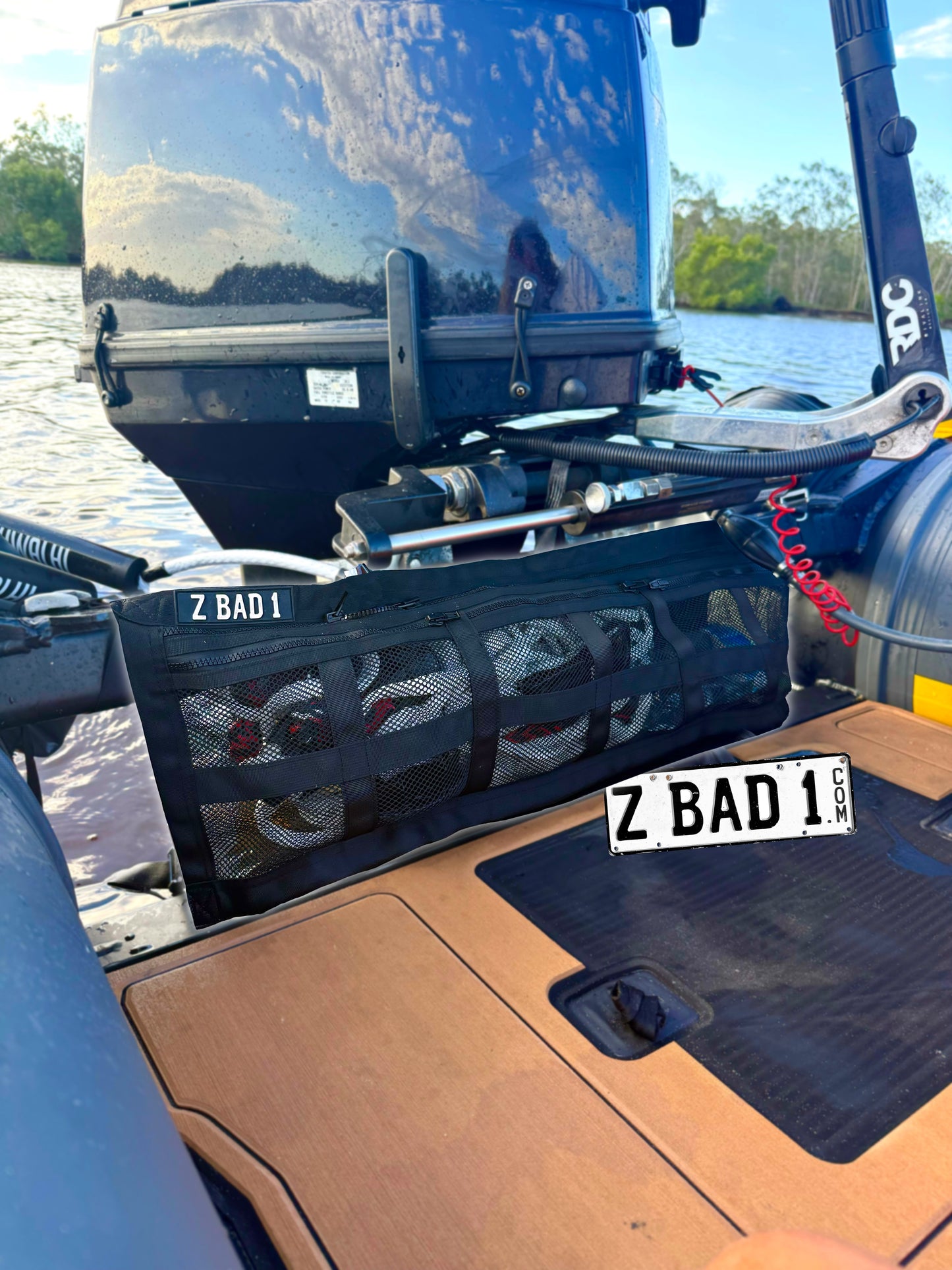 ZBAD1 half length marine cargo net strapped across the transom of a boat near the outboard, holding gear