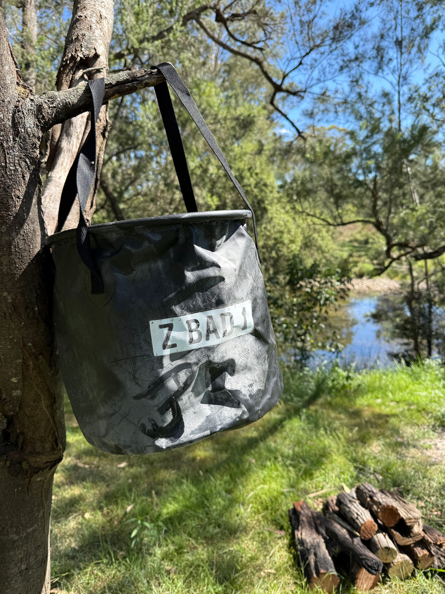 ZBAD1 flexi stowaway bucket hanging by its straps from a tree branch at a campsite