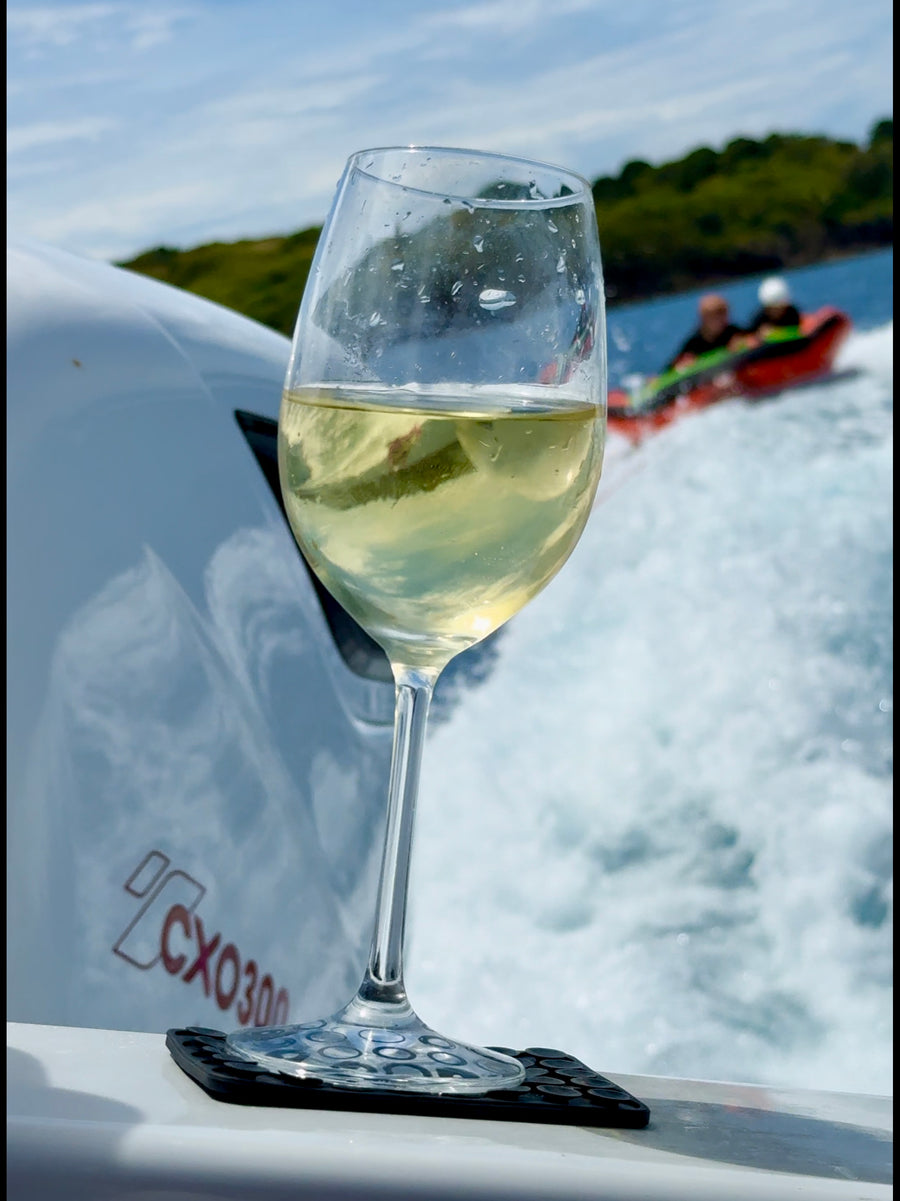 Wine glass gripped by a ZBAD1 grip mat on a moving boat, inflatable towing behind